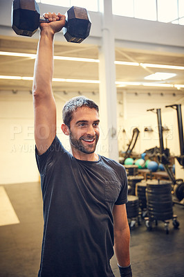 Buy stock photo Cropped shot of a handsome young man working out with a dumbbell in the gym