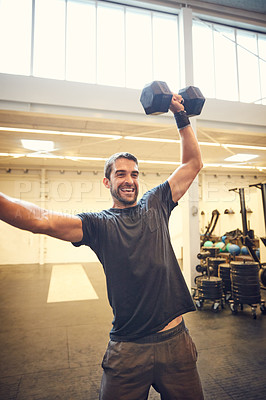 Buy stock photo Cropped shot of a handsome young man working out with a dumbbell in the gym