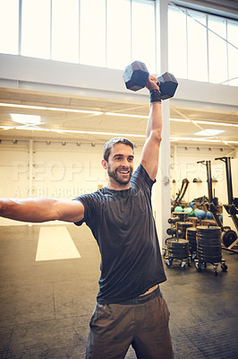 Buy stock photo Cropped shot of a handsome young man working out with a dumbbell in the gym