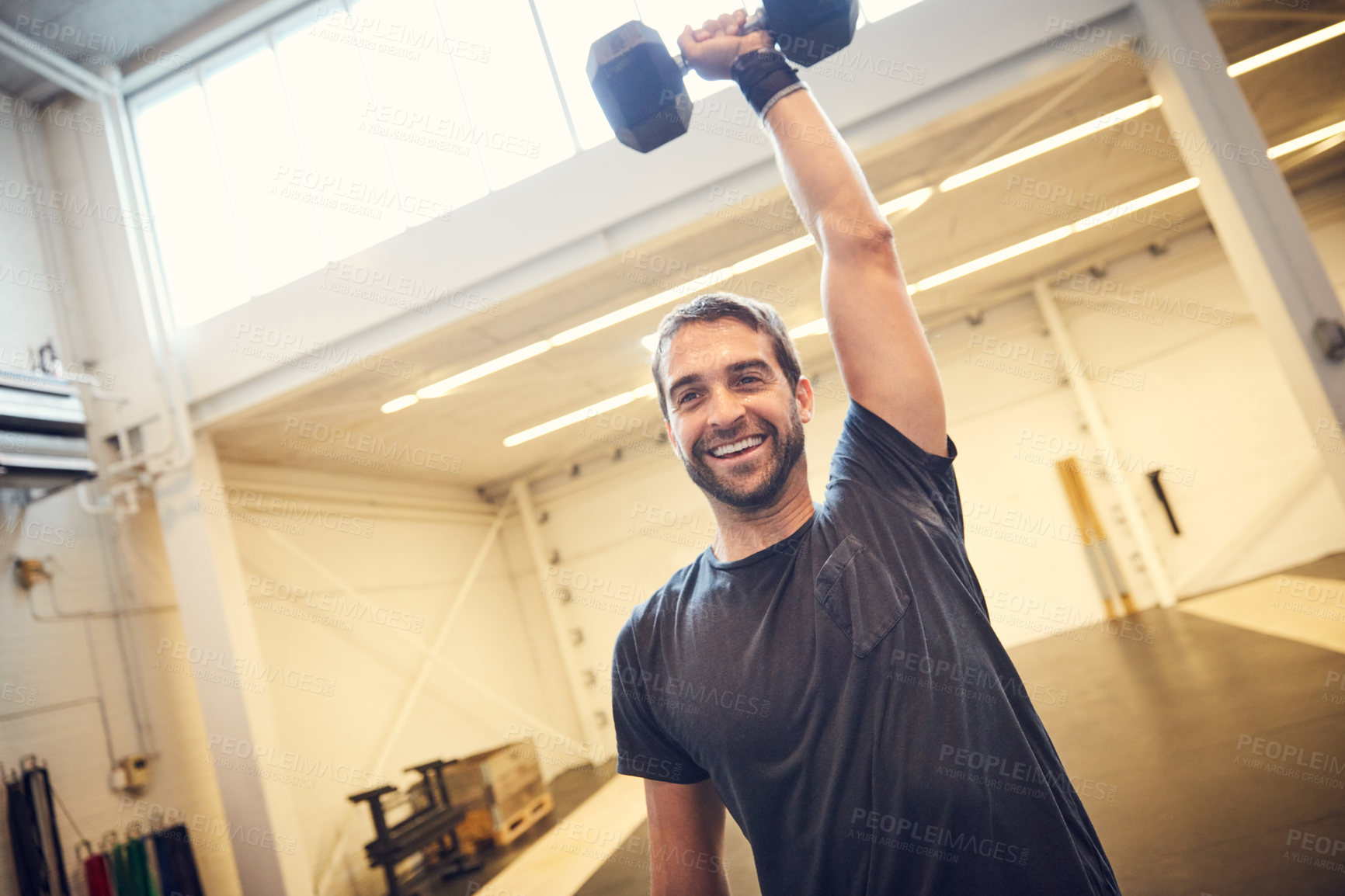 Buy stock photo Low angle shot of a handsome young man working out with a dumbbell in the gym