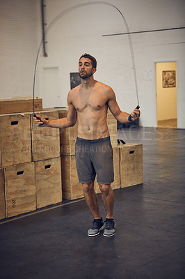 Buy stock photo Full length shot of a handsome young man skipping while working out in the gym