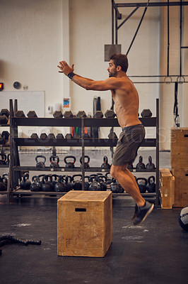 Buy stock photo Full length shot of a handsome young man box jumping while working out in the gym