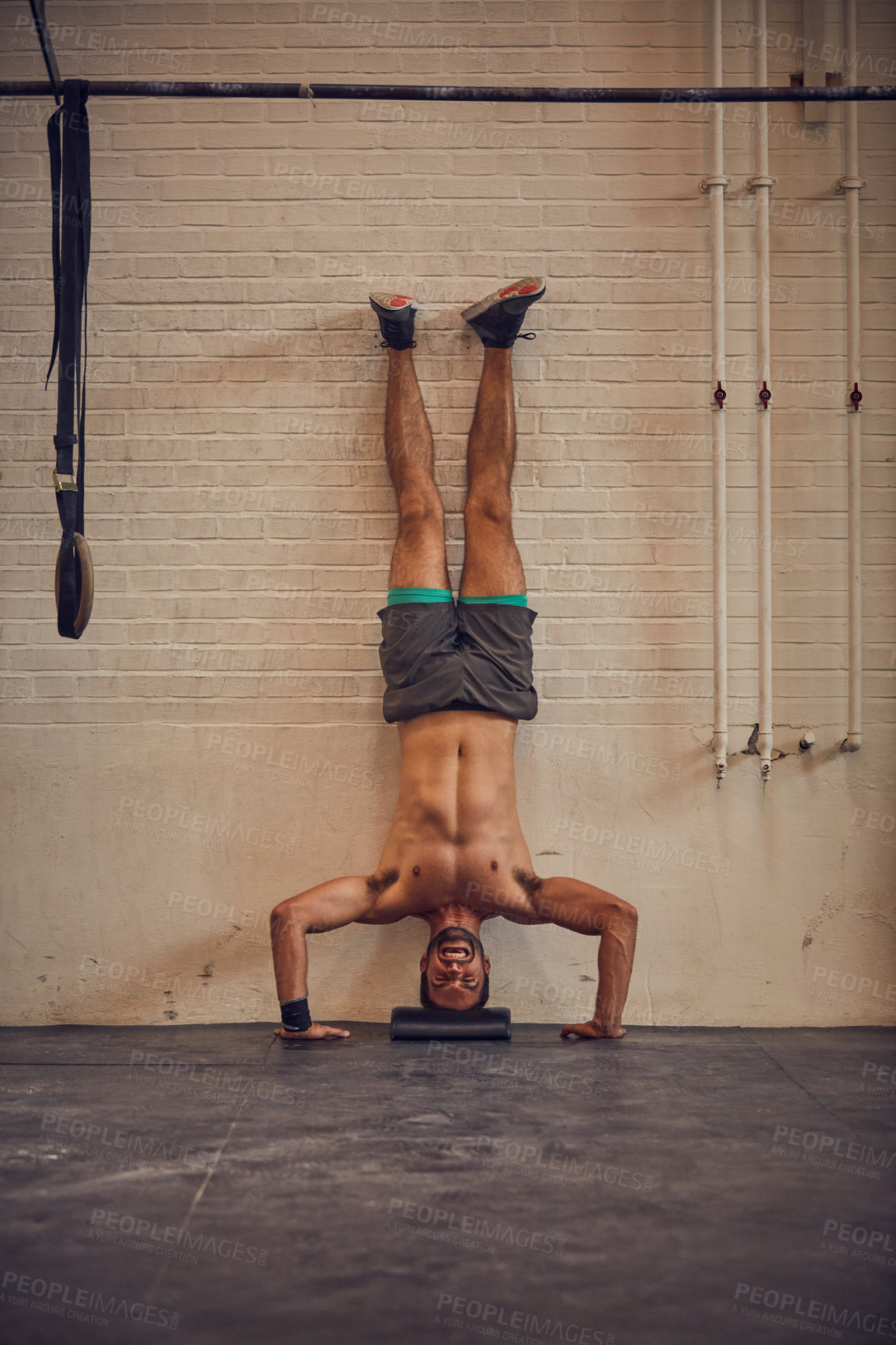 Buy stock photo Full length shot of a handsome young man doing handstands while working out in the gym