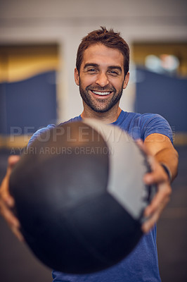 Buy stock photo Cropped portrait of a handsome young man working out with a medicine ball in the gym
