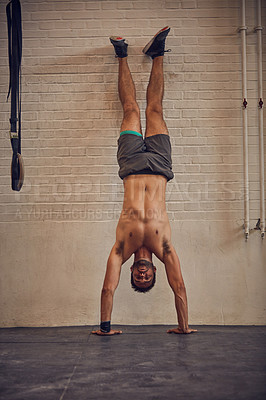 Buy stock photo Full length portrait of a handsome young man doing handstands while working out in the gym