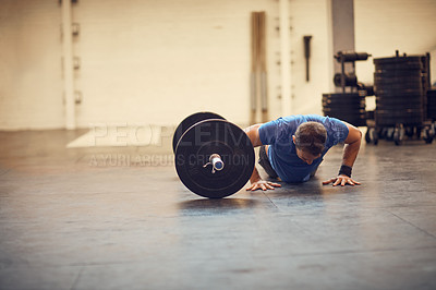 Buy stock photo Full length shot of a handsome young man doing pushups while working out in the gym