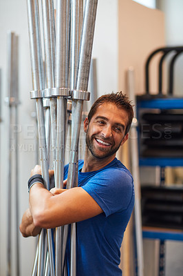 Buy stock photo Cropped shot of a handsome young man carrying equipment while working out in the gym