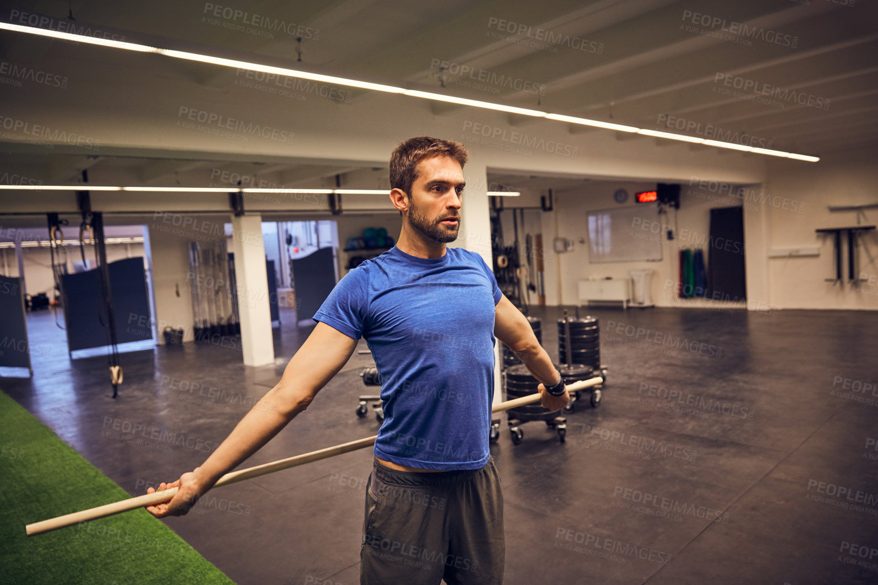 Buy stock photo Cropped shot of a handsome young man working out with a stick in the gym