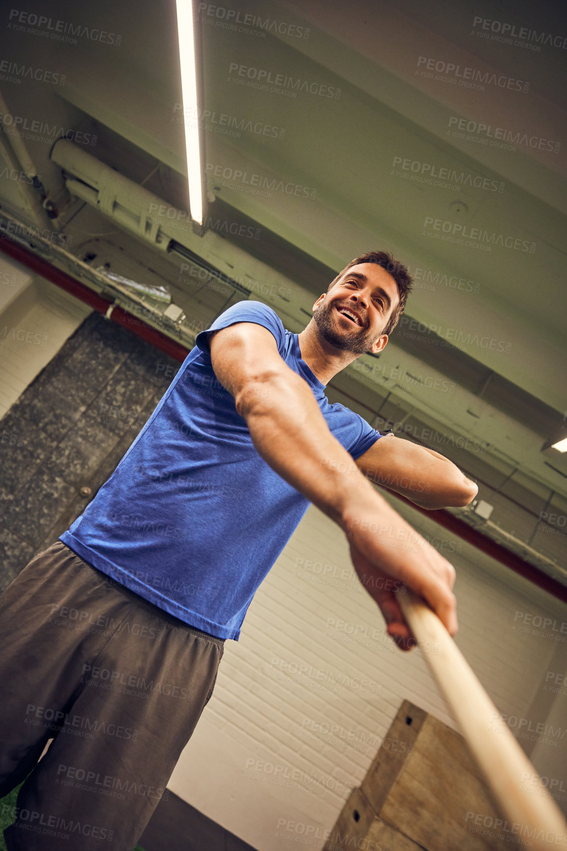 Buy stock photo Low angle shot of a handsome young man working out with a stick in the gym