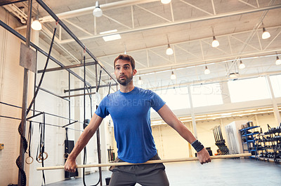 Buy stock photo Cropped shot of a handsome young man working out with a stick in the gym