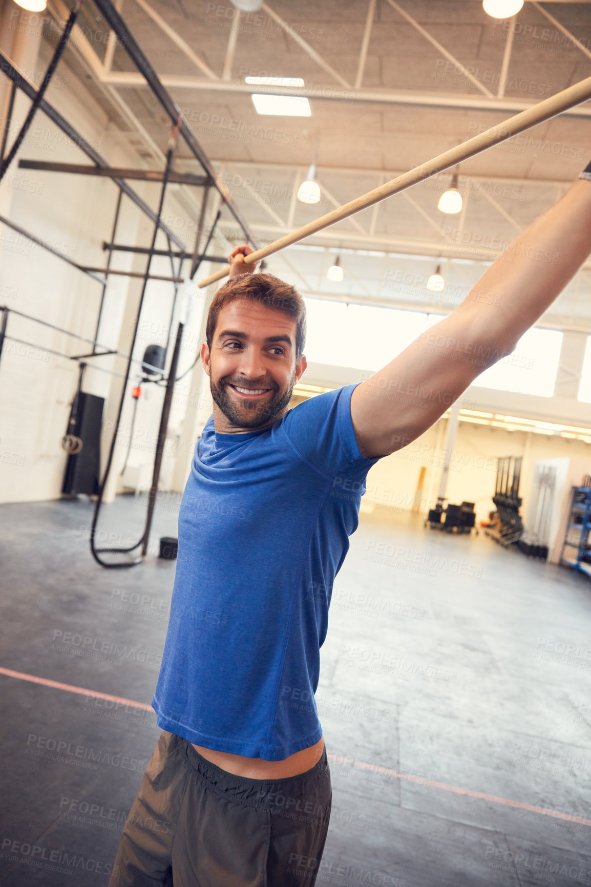 Buy stock photo Cropped shot of a handsome young man working out with a stick in the gym