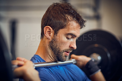 Buy stock photo Cropped shot of a handsome young man lifting weights while working out in the gym
