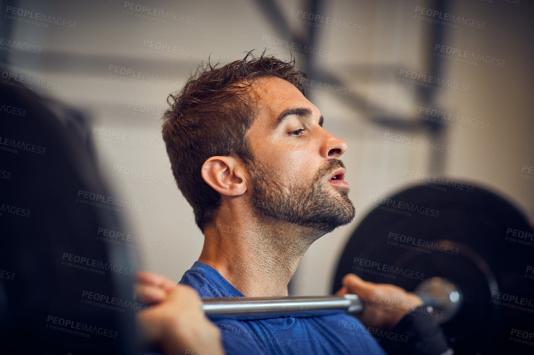 Buy stock photo Cropped shot of a handsome young man lifting weights while working out in the gym