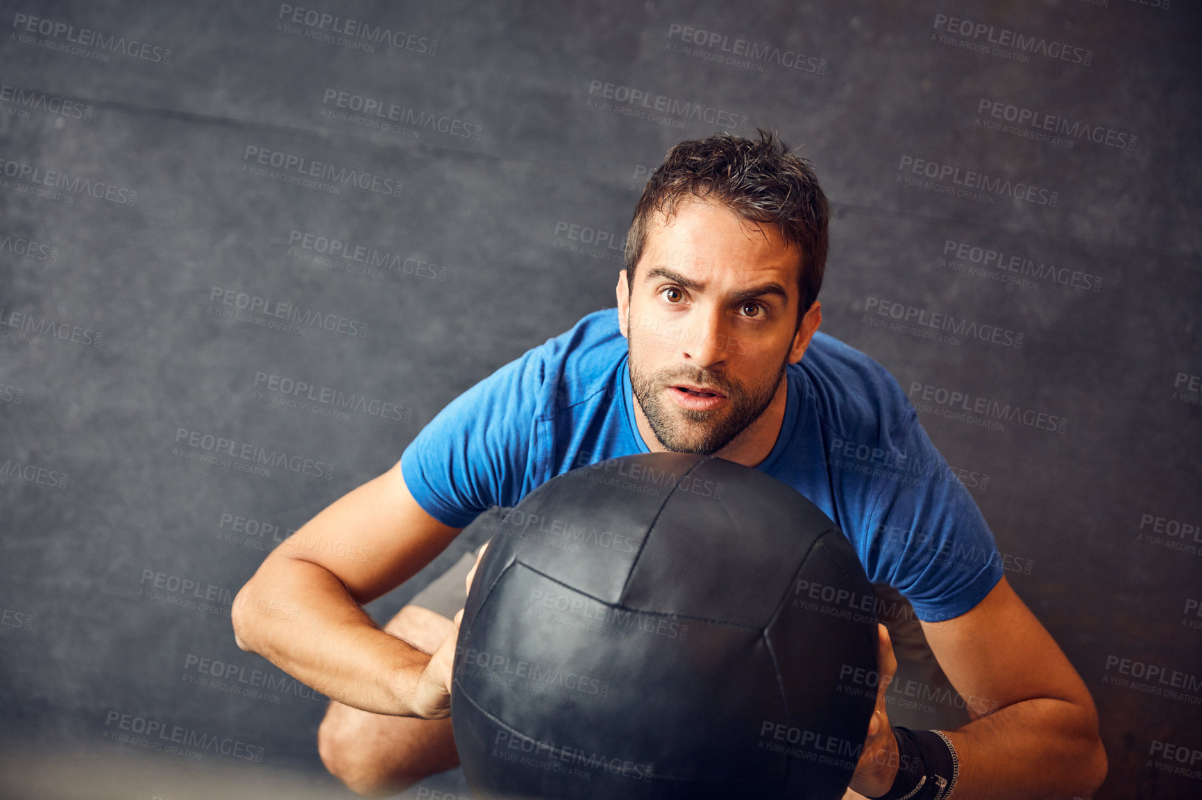 Buy stock photo High angle shot of a handsome young man working out with a medicine ball in the gym