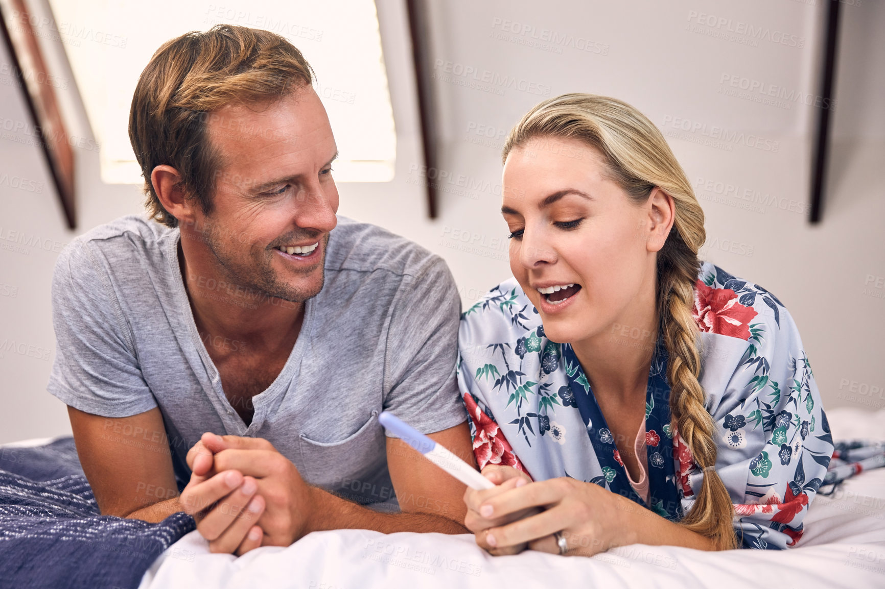 Buy stock photo Shot of a beautiful young couple feeling cheerful after taking a home pregnancy test