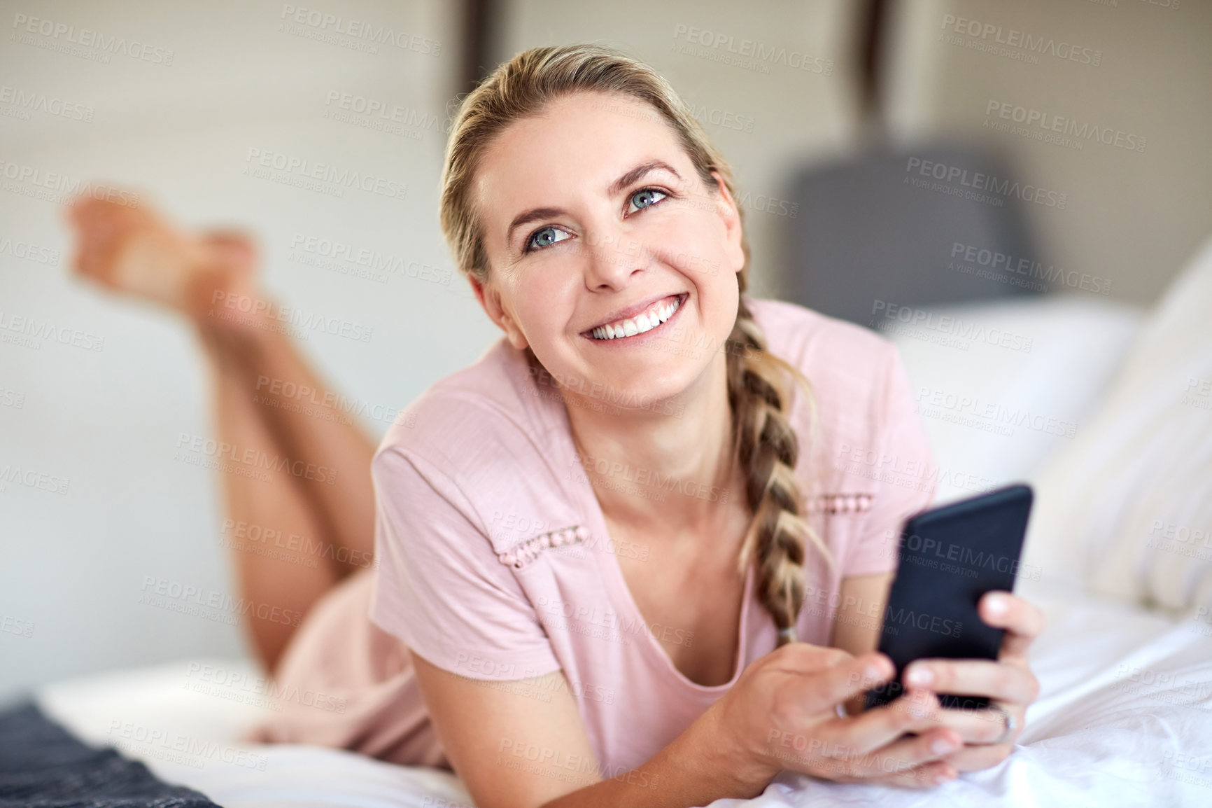 Buy stock photo Shot of an attractive young woman using her cellphone while lying on her bed in her bedroom at home