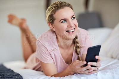 Buy stock photo Shot of an attractive young woman using her cellphone while lying on her bed in her bedroom at home