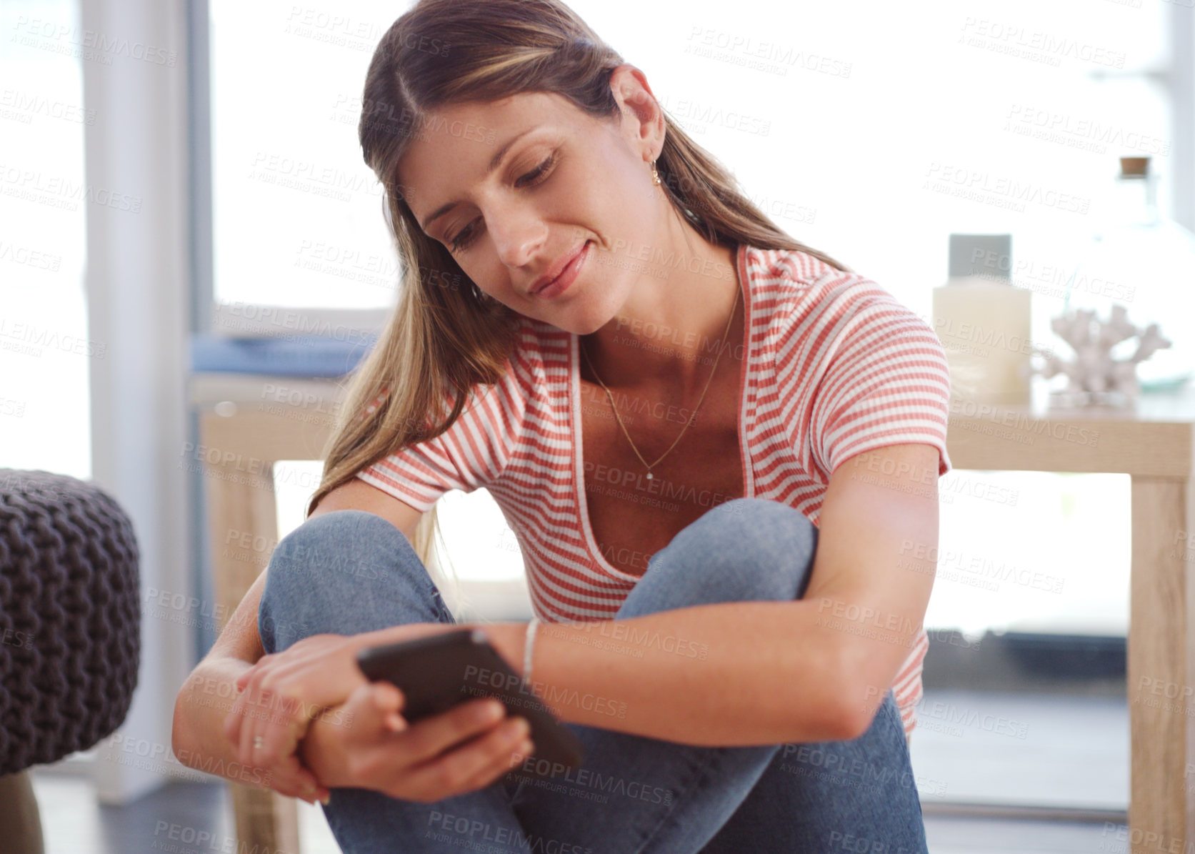 Buy stock photo Shot of an attractive woman using her cellphone while relaxing at home