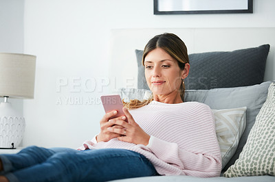 Buy stock photo Shot of an attractive woman using her cellphone while relaxing at home