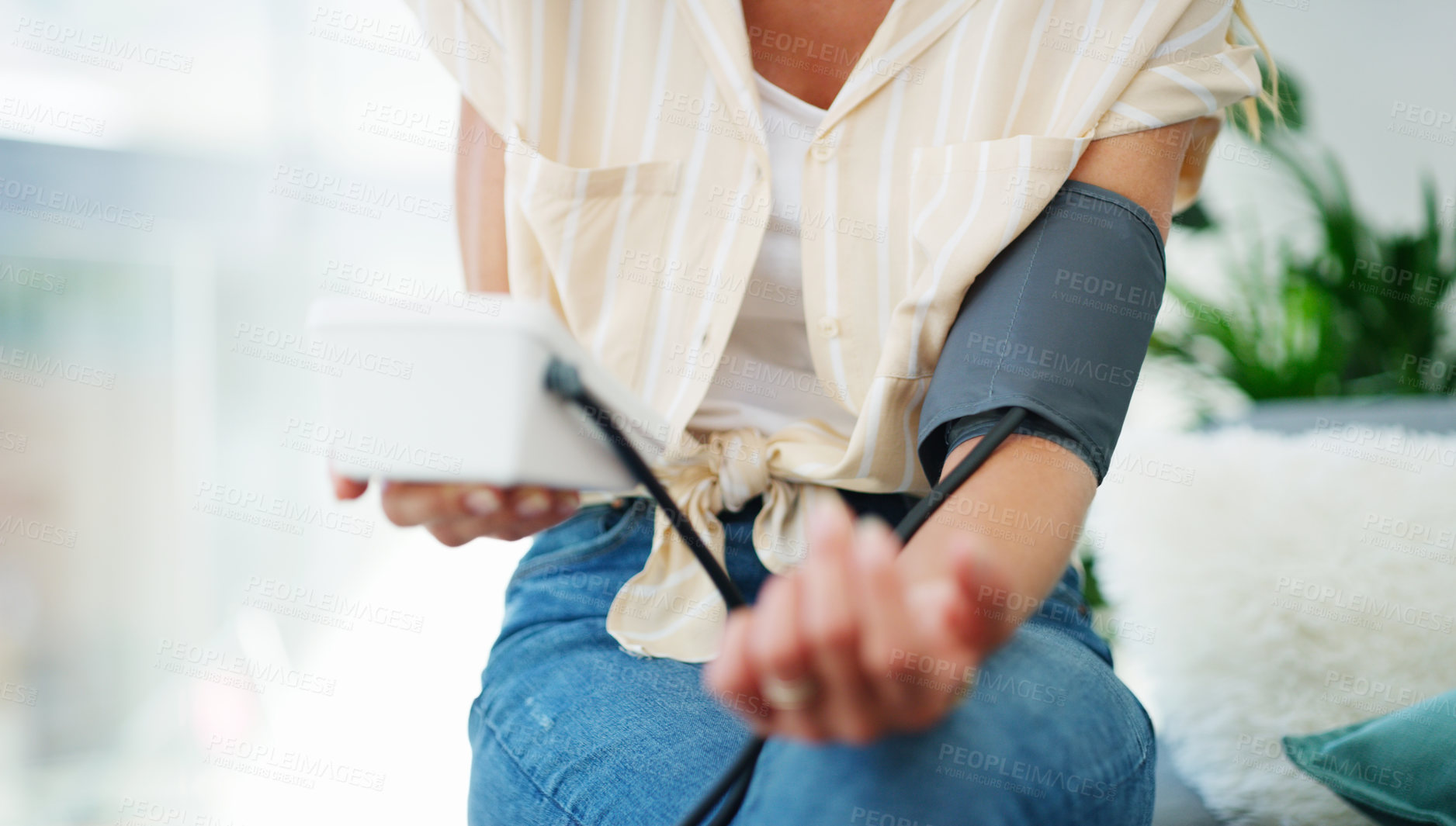Buy stock photo Cropped shot of a woman checking her blood pressure at home