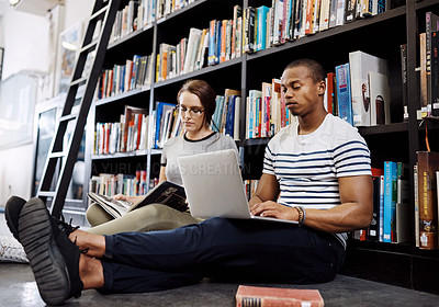 Buy stock photo Shot of two young sitting on the floor and studying in a college library