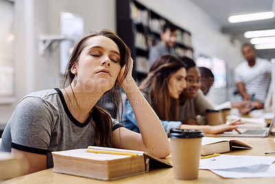 Buy stock photo Shot of a young woman looking tired while studying in a college library in the library