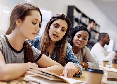 Buy stock photo Shot of two young women having a discussion in a college library