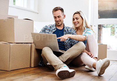Buy stock photo Shot of a young couple using a laptop while moving house