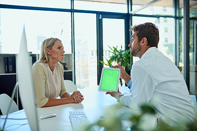 Buy stock photo Shot of a doctor using his digital tablet while consulting a female patient in his office