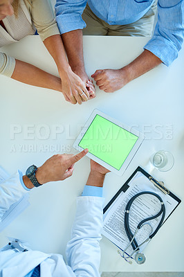 Buy stock photo High angle shot of an unrecognizable doctor using a digital tablet while consulting a couple in his office