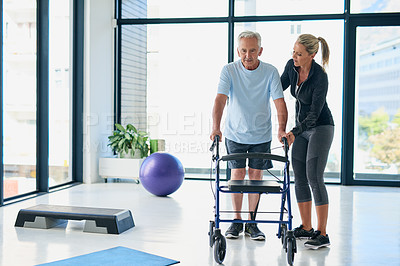 Buy stock photo Full length shot of a friendly female physiotherapist helping a senior use a walker in a fitness centre