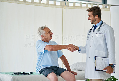 Buy stock photo Cropped shot of a young male doctor shaking hands with an elderly patient in his office