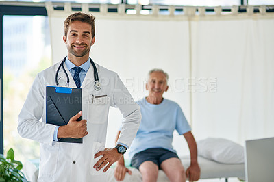 Buy stock photo Cropped portrait of a handsome young doctor standing in his office with an elderly patient in the background