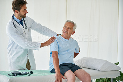 Buy stock photo Cropped shot of a young male doctor examining a senior patient with back pain in his office