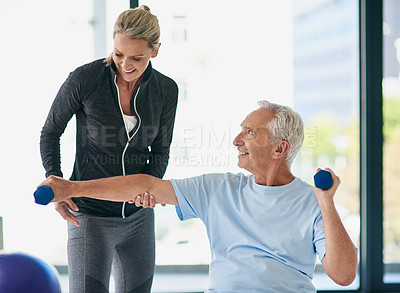 Buy stock photo Cropped shot of a happy senior man working out with weights with the help of a physiotherapist