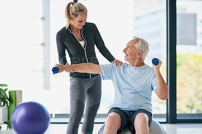 Buy stock photo Cropped shot of a friendly female physiotherapist helping her senior patient work out with weights