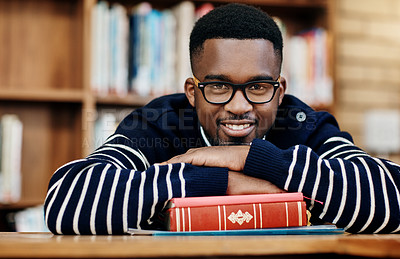 Buy stock photo African man, book and portrait at college, library and happy for studying, learning or development. Person, student and smile with laying at desk with research for assessment, exam or quiz in hall