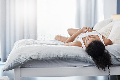 Buy stock photo Shot of an unrecognizable young woman lying on her bed facing up