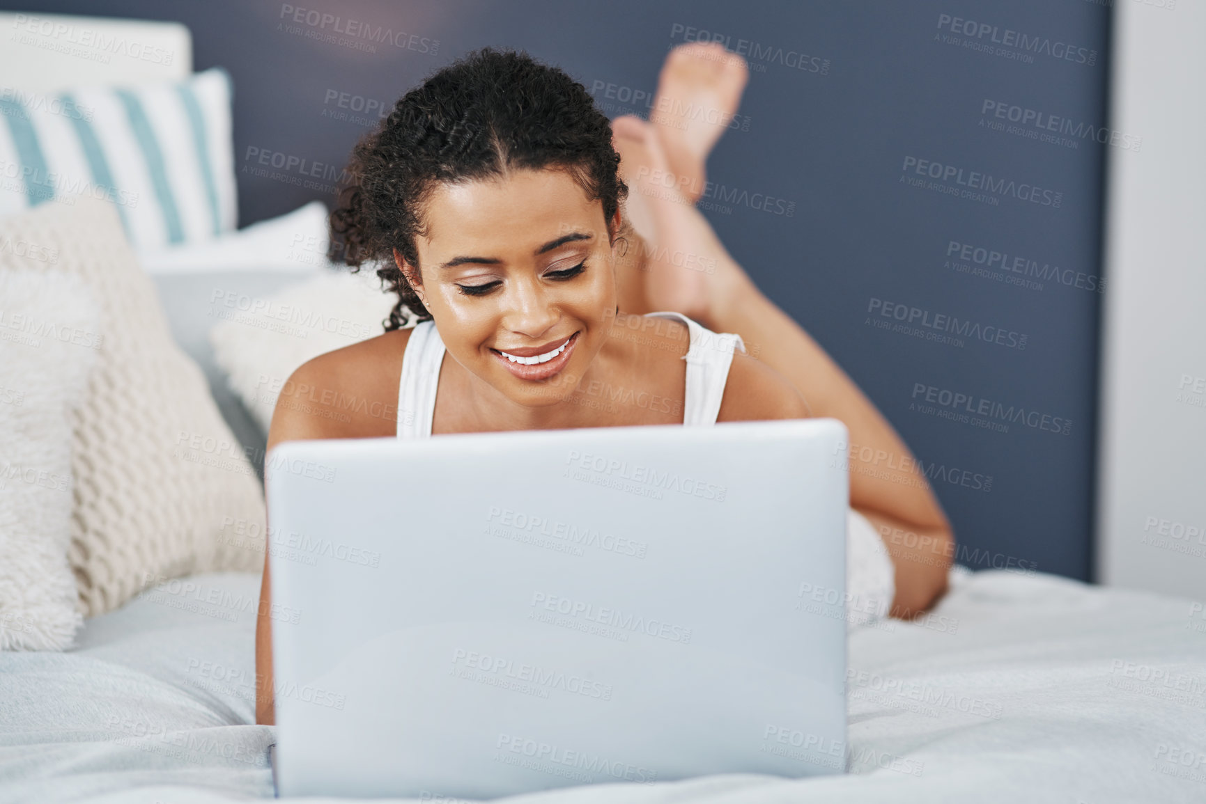 Buy stock photo Shot of an attractive young woman using her laptop while relaxing on her bed at home