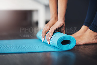 Buy stock photo Cropped shot of an unrecognizable young woman rolling up her yoga mat in her bedroom