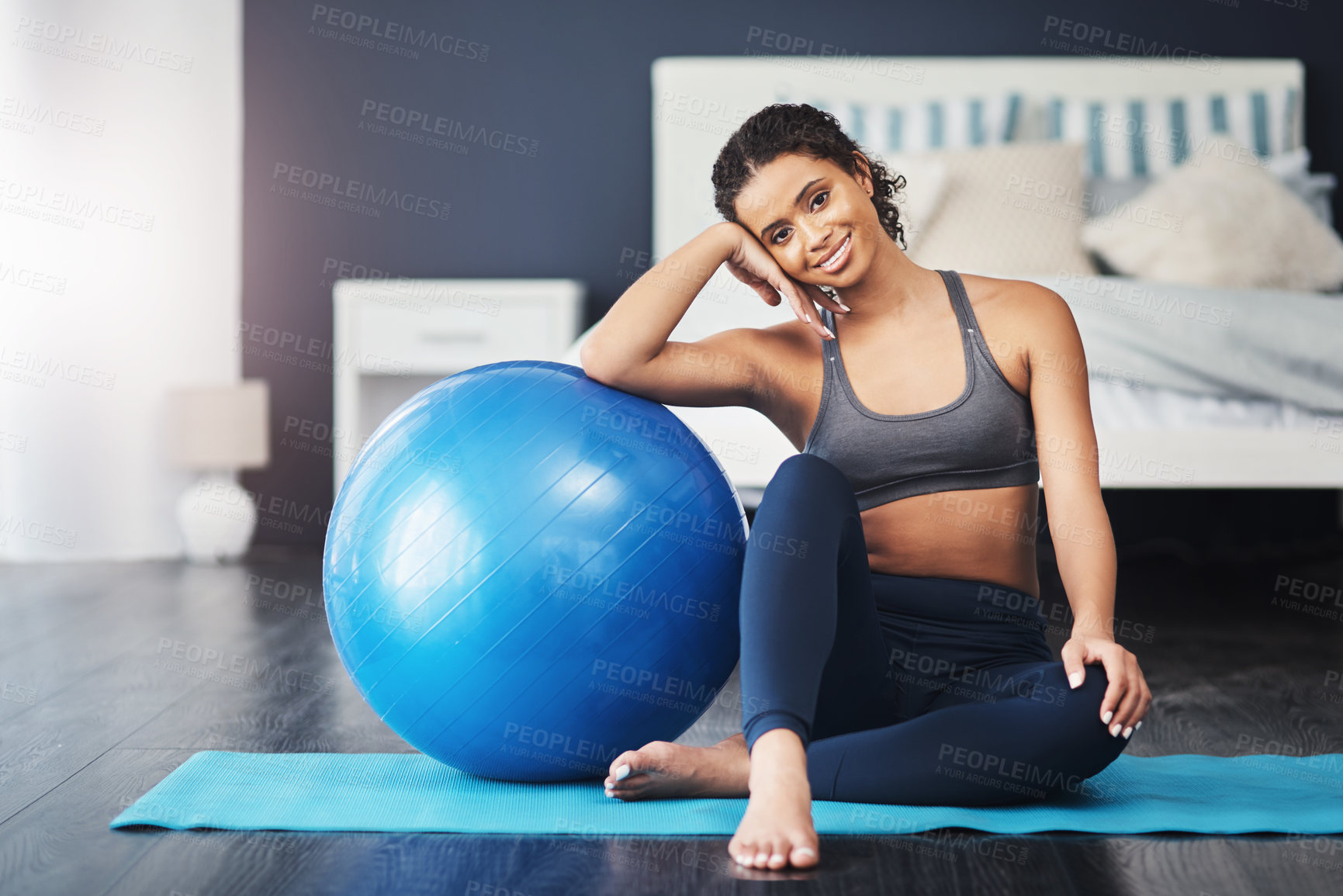 Buy stock photo Shot of an attractive young woman resting on her exercise ball while sitting on her yoga mat in her bedroom
