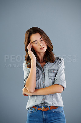 Buy stock photo Studio shot of an attractive young woman suffering with a headache against a grey background