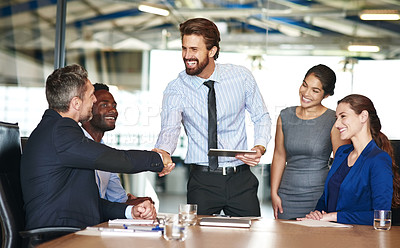 Buy stock photo Shot of two businesspeople shaking hands while in a meeting with colleagues