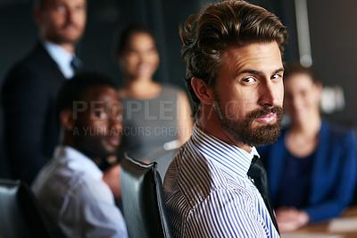 Buy stock photo Shot of a businessman sitting in an office with colleagues in the background
