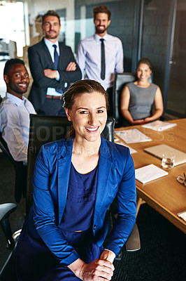 Buy stock photo Portrait of a smiling businesswoman sitting in an office with colleagues in the background