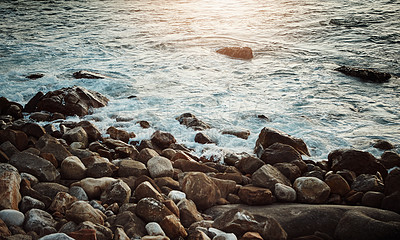 Buy stock photo Shot of water crashing against some boulders at the beach