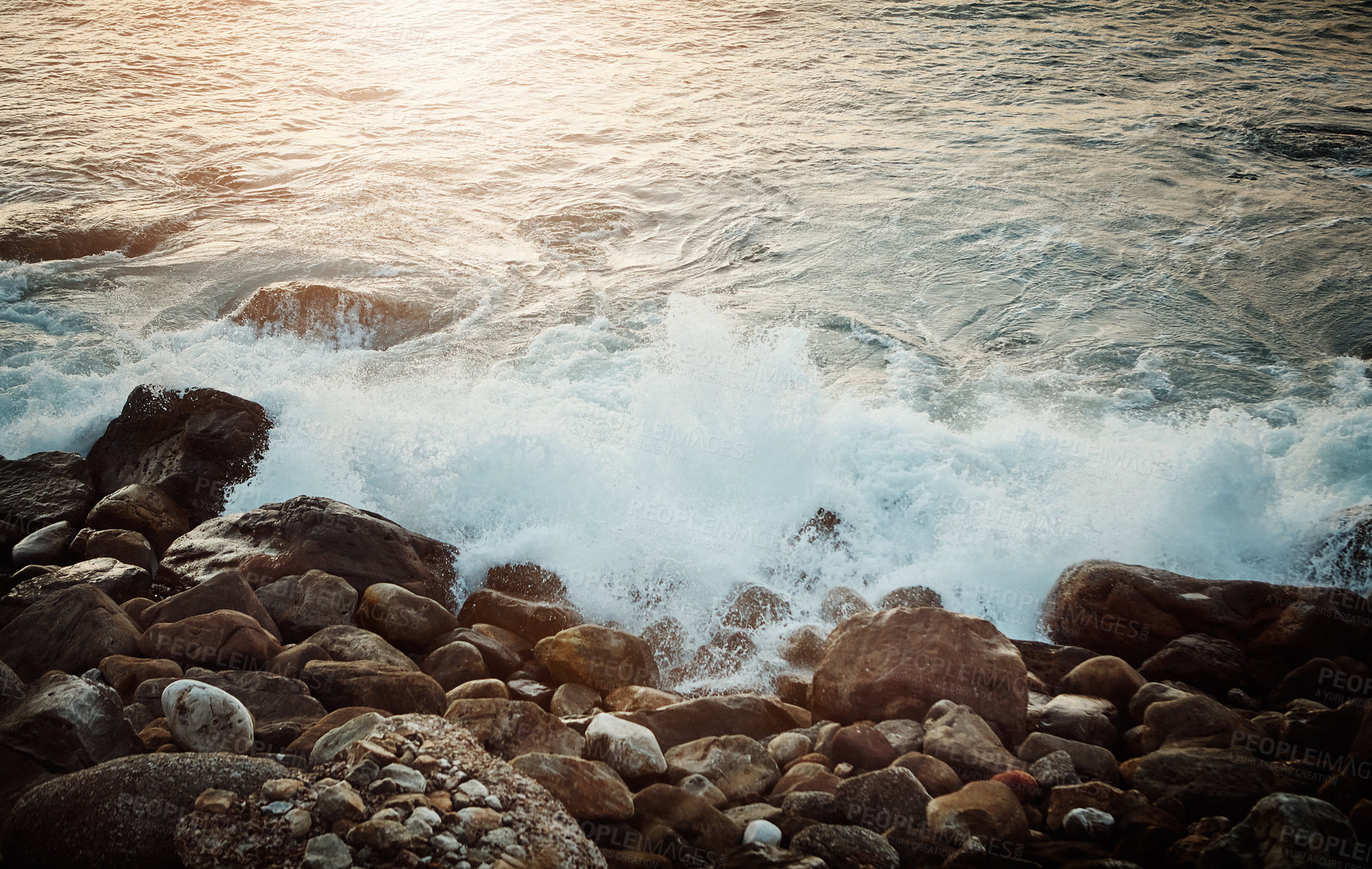 Buy stock photo Shot of water crashing against some boulders at the beach