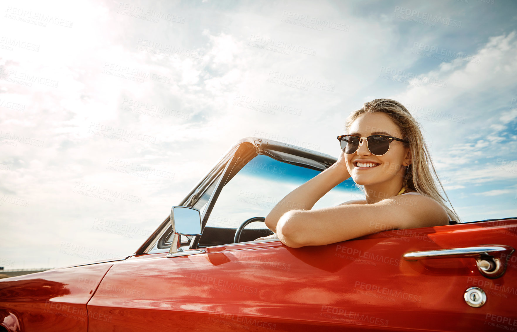 Buy stock photo Shot of a happy young woman enjoying a summer’s road trip