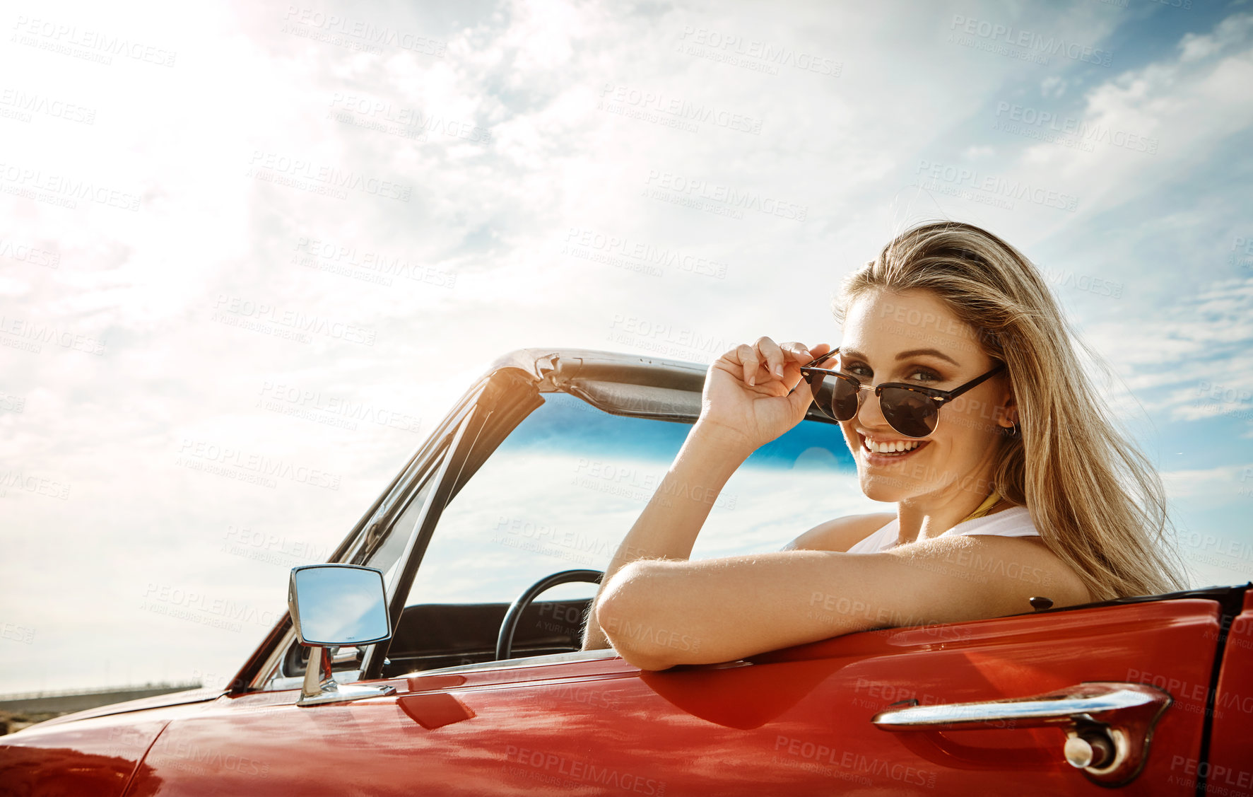 Buy stock photo Shot of a happy young woman enjoying a summer’s road trip