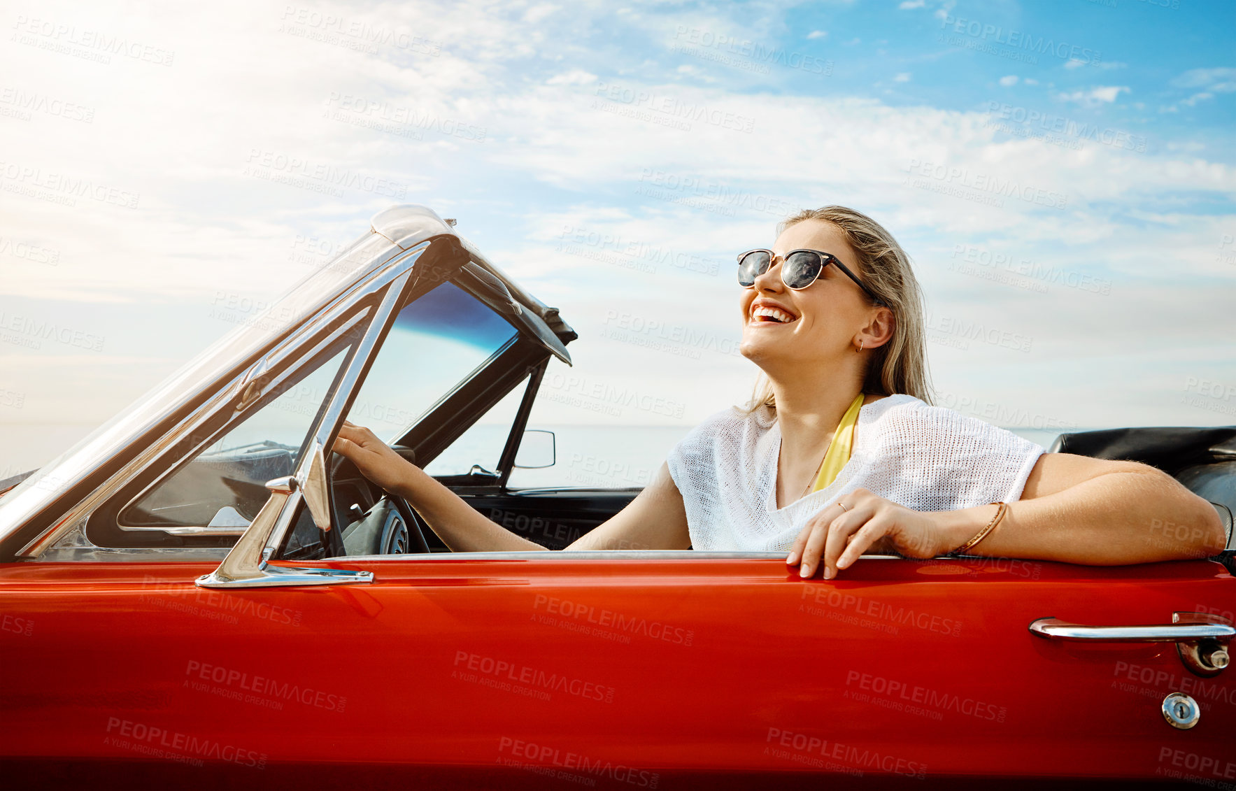 Buy stock photo Shot of a happy young woman enjoying a summer’s road trip